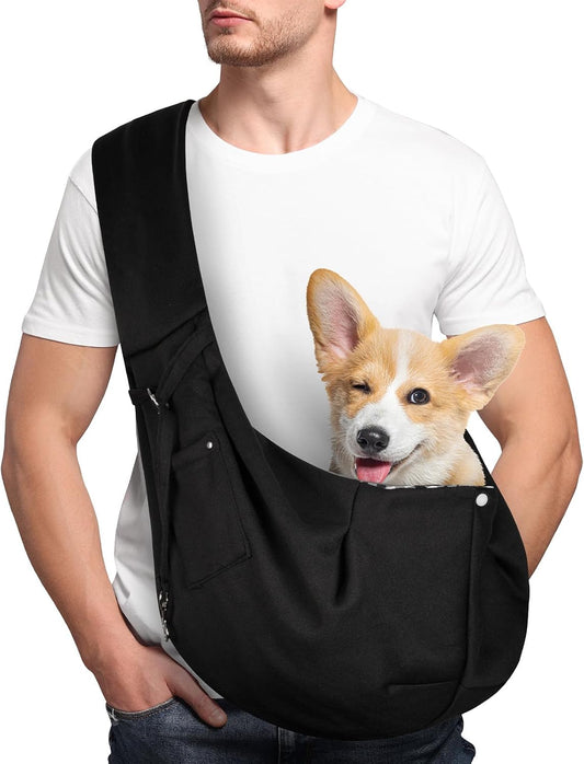 Black adjustable dog sling carrier with a small dog sitting inside